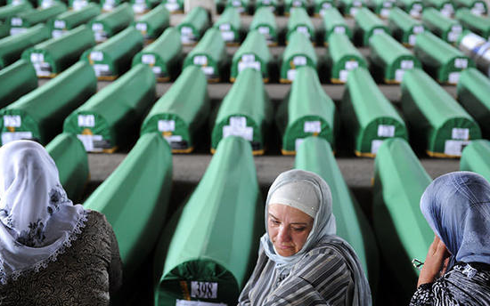 Bosnian Muslim women cry and pray among 520 caskets stocked in an abandoned factory hangar, in preparation for a mass burial ceremony at the Srebrenica Memorial Cemetery, in Potocari on July 10, 2012 (AFP Photo)